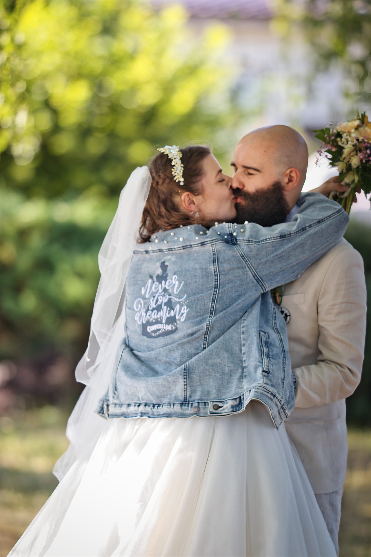 Le marié embrasse tendrement la mariée sous les arbres
